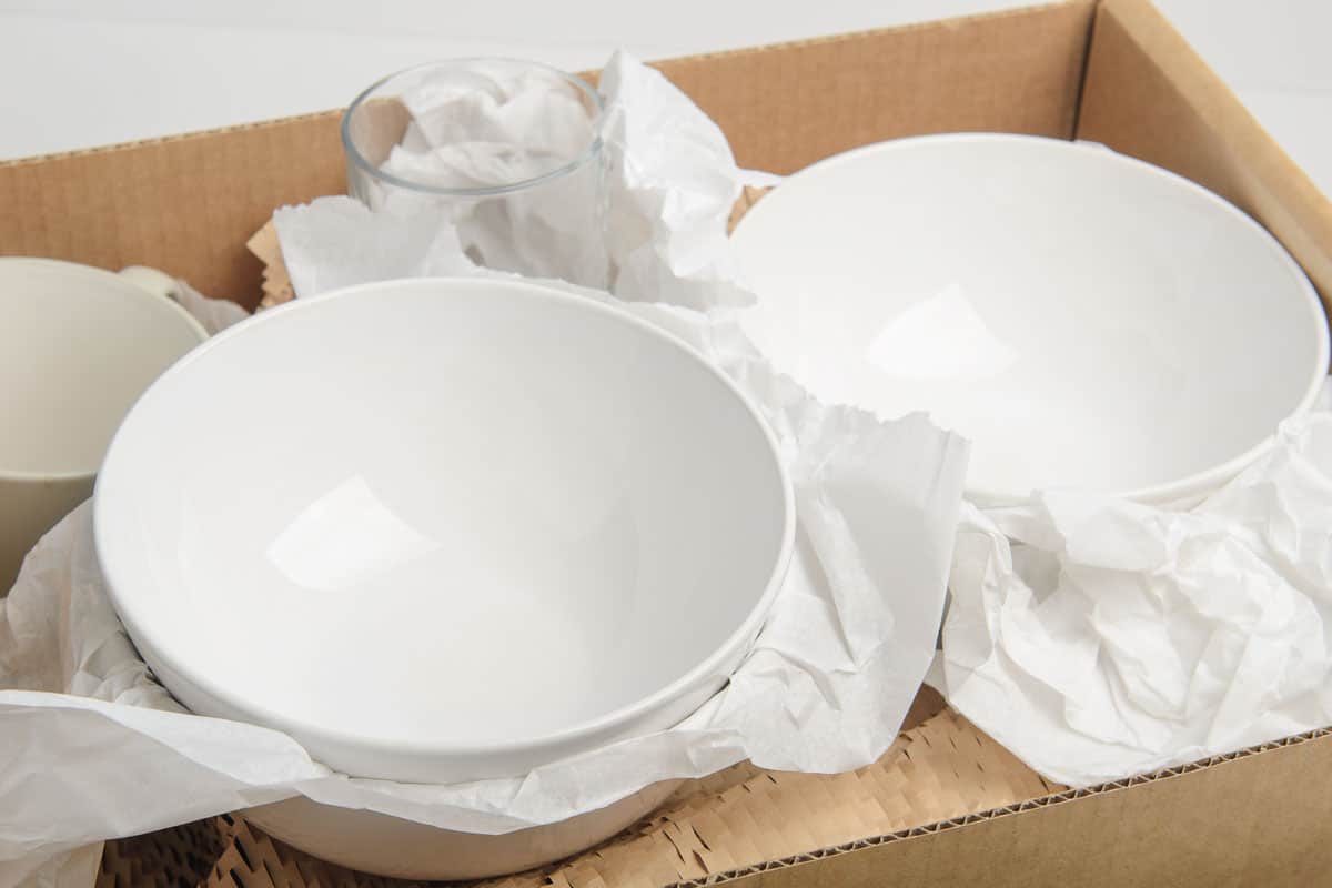 Clean white Bowls dishes in paper packed in cardboard box