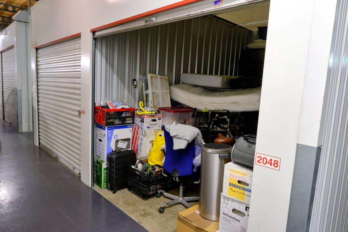 Indoor storage unit with open door and household goods in a self storage facility.