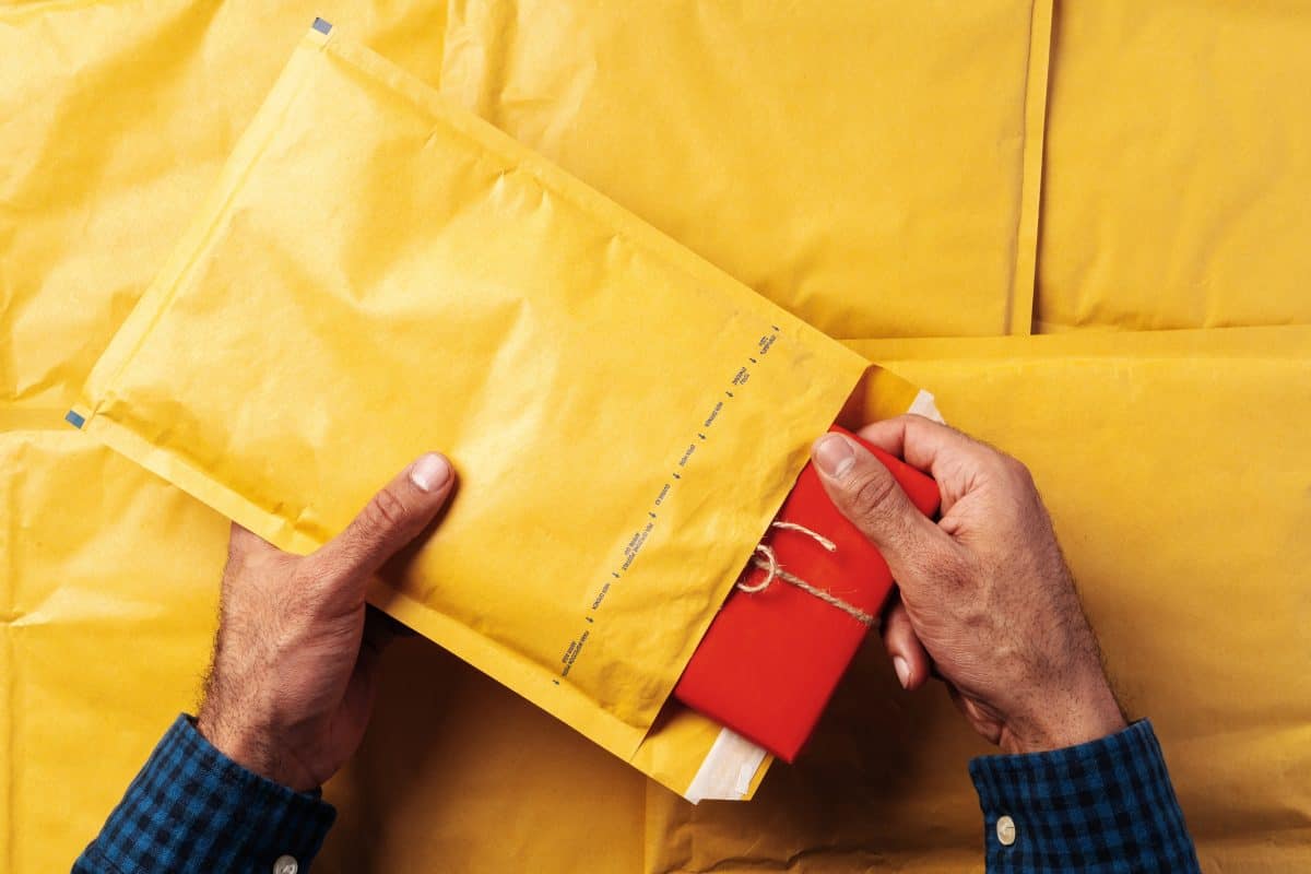 Male hands packing yellow bubble envelopes for shipping.