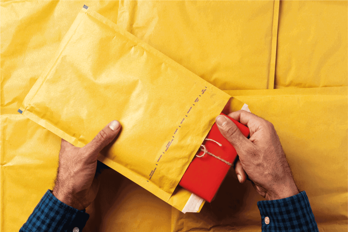 Male hands packing yellow bubble envelopes for shipping