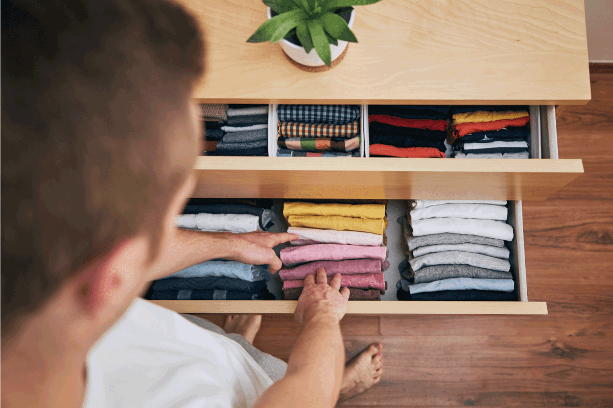 Man choosing from orderly folded t-shirts in drawer.
