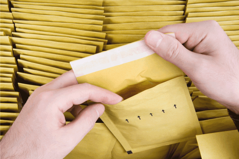 Self sealed mailing envelope quality inspection. Male hands open one yellow bubble mailer out of a bunch of shipping airmail packets