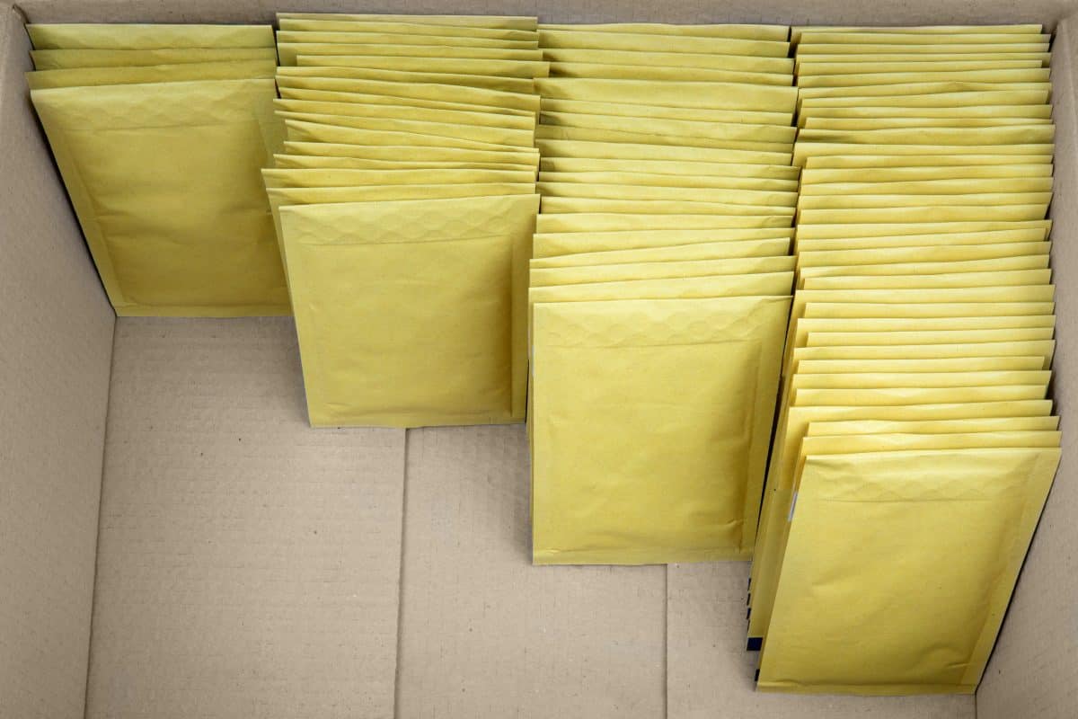 Sorting and packing yellow shipping envelopes in a delivery box.