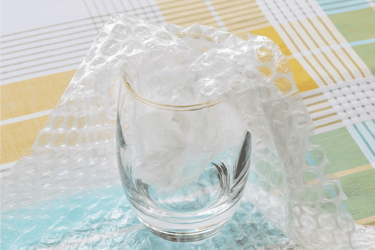 Thick bottom glass half packaged with transparent bubble wrap on a checkered tablecloth