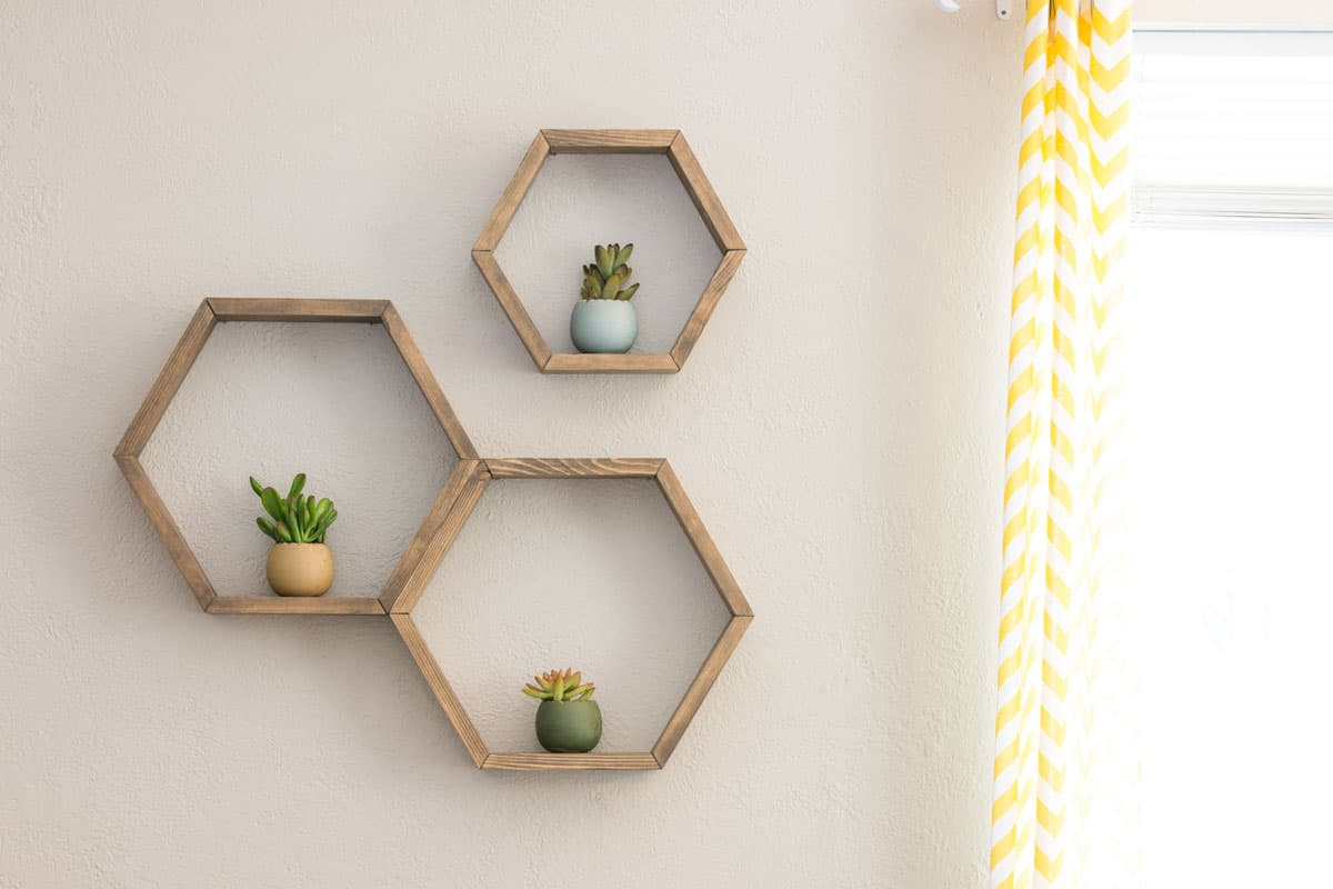 Three decorative wooden, floating, hexagon wall shelves, with decorative plants
