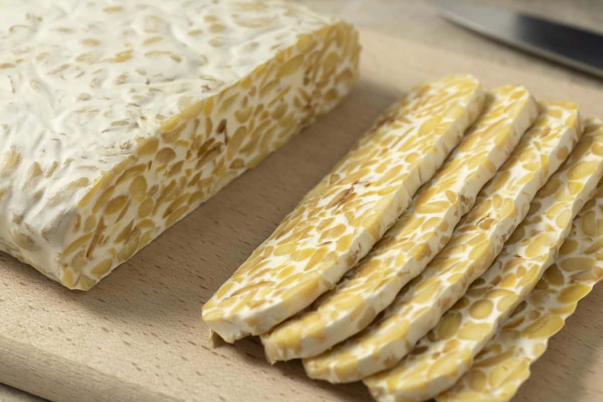 Traditional vegetarian tempeh sliced on a cutting board close up

