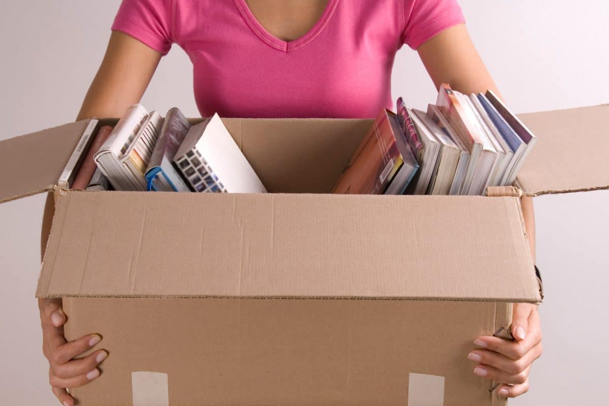Woman holding open cardboard box of books