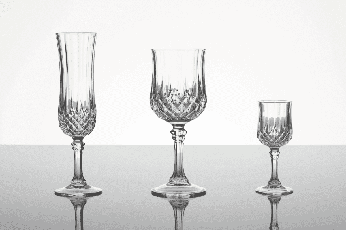 champagne flute, wine glass and liqueur glass made out of cut glass (crystal glass or lead glass), on plain gray shiny surface