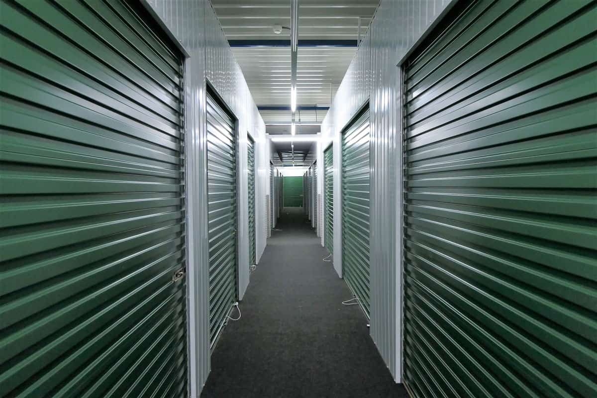 hallway of self storage units for rent with green rolling doors