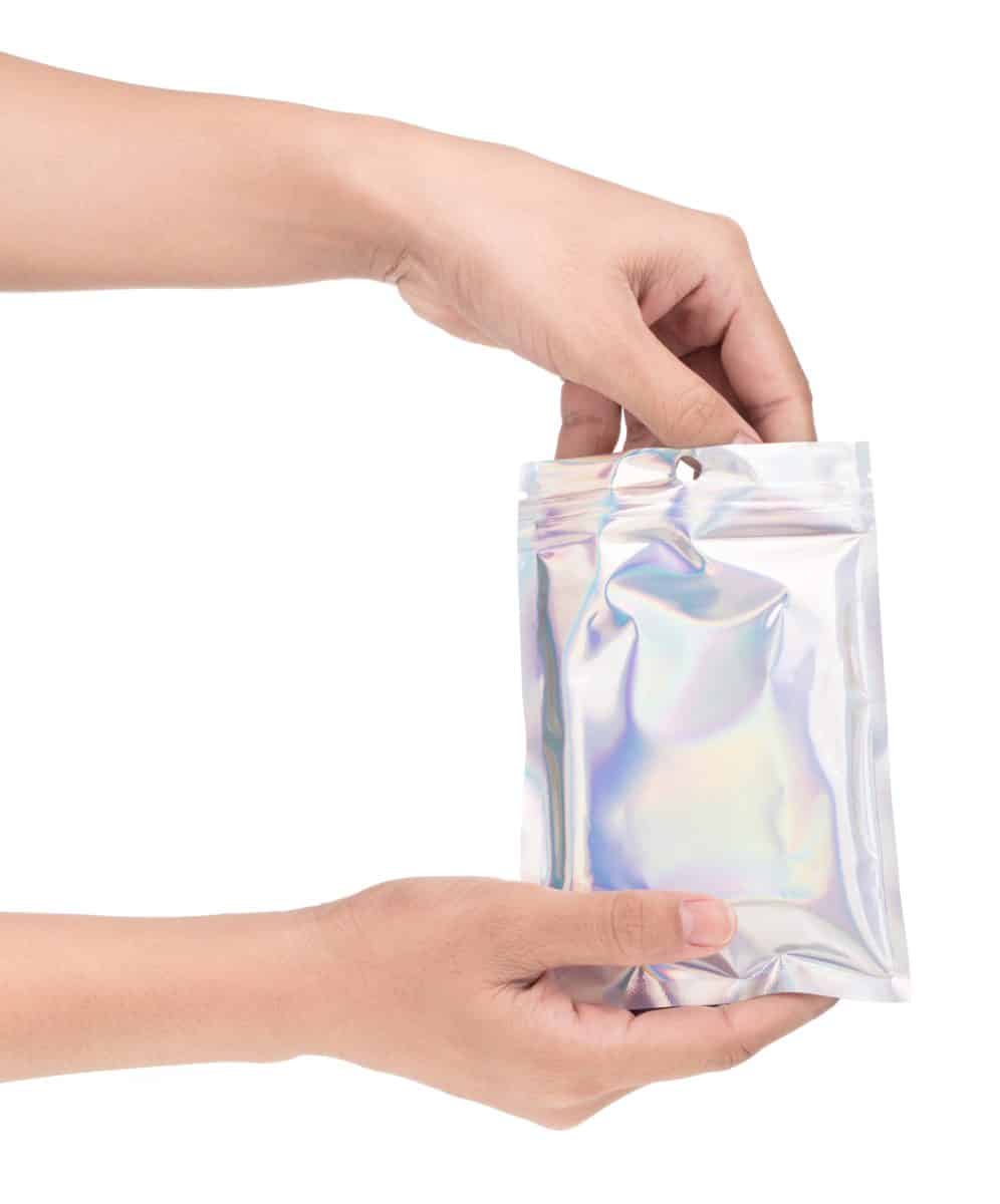 hand holding Aluminum foil bag Plastic Laser Mylar Foil Zip Lock Bag isolated on white background.
