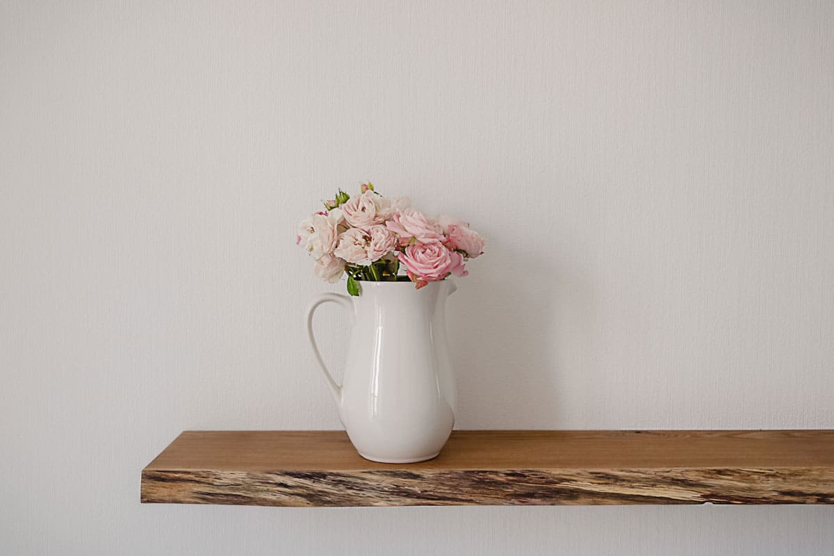 loating wooden shelf with a big ceramic jug of pink pastel flowers