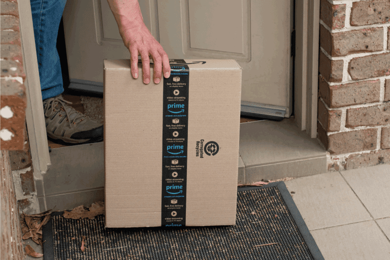 man picking up delivered amazon package on his doorstep. Is Amazon Packaging Tape Compostable