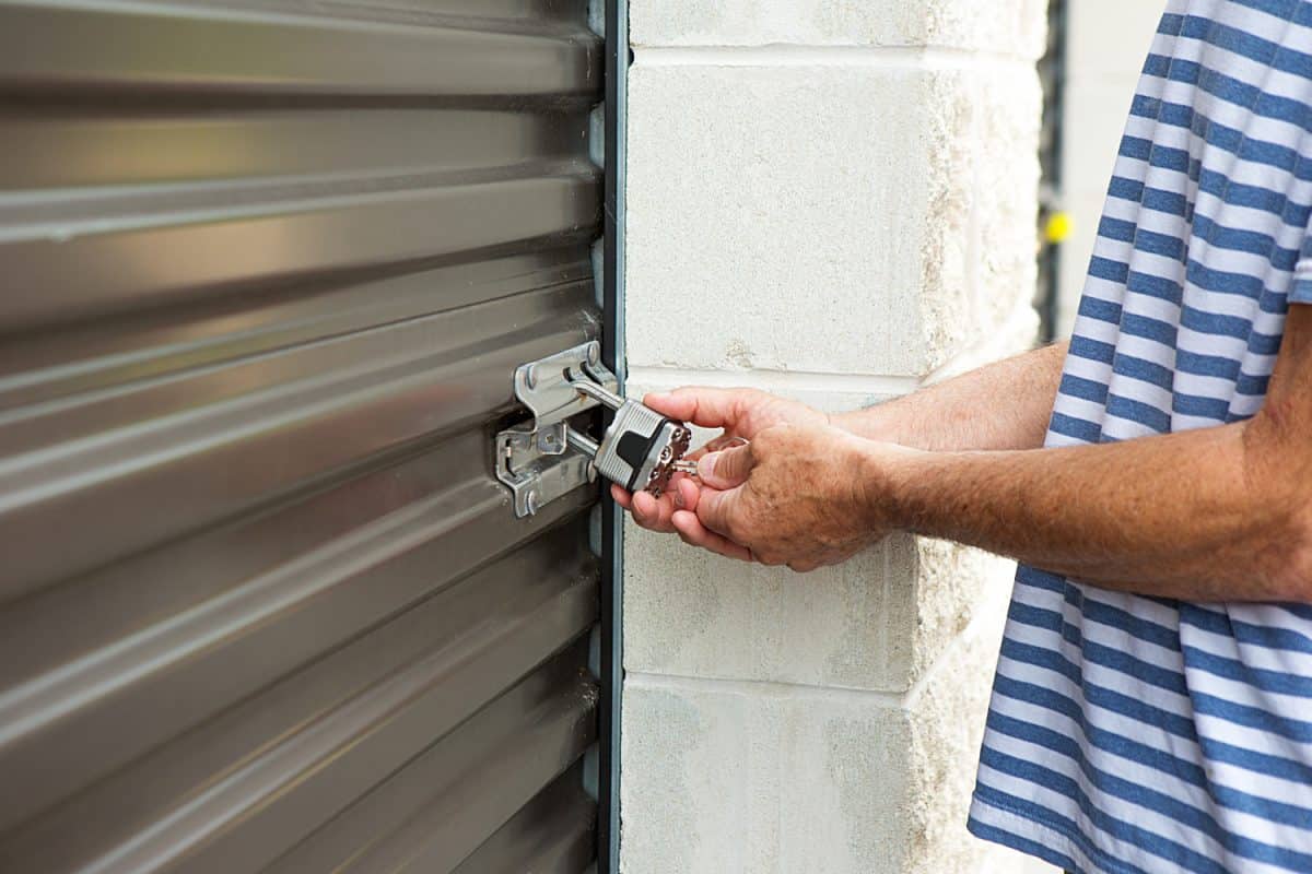 senior male using his key to open a lock at his storage warehouse

