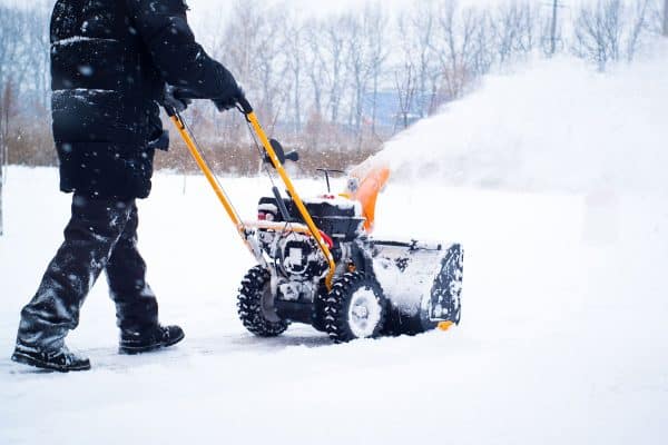 A man cleans snow from sidewalks with snowblower, How To Store Snowblower In Garage?