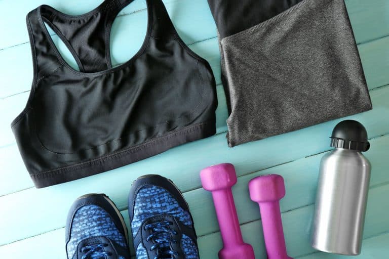 Athlete's set with female clothing, dumbbells and bottle of water on blue wooden background, How To Organize Athletic Clothes [5 Great Tips!]