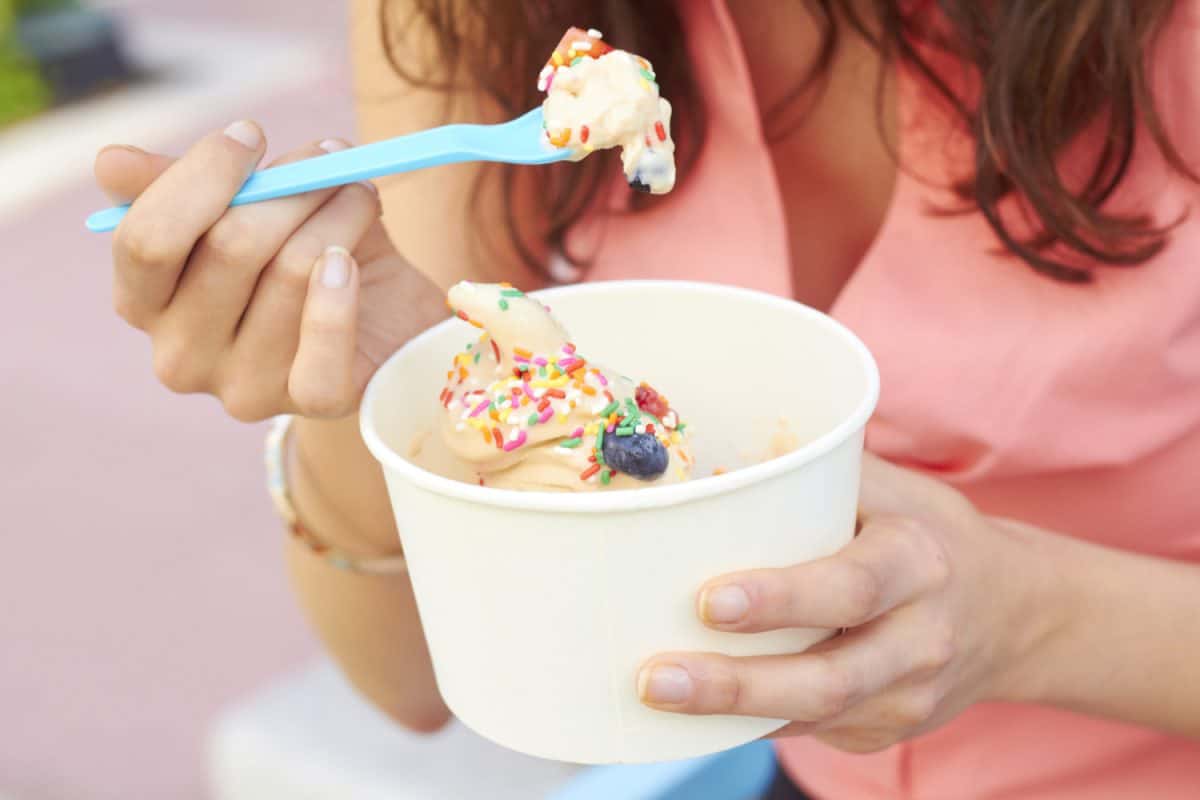 a woman in pink, eating a yogurt outdoor