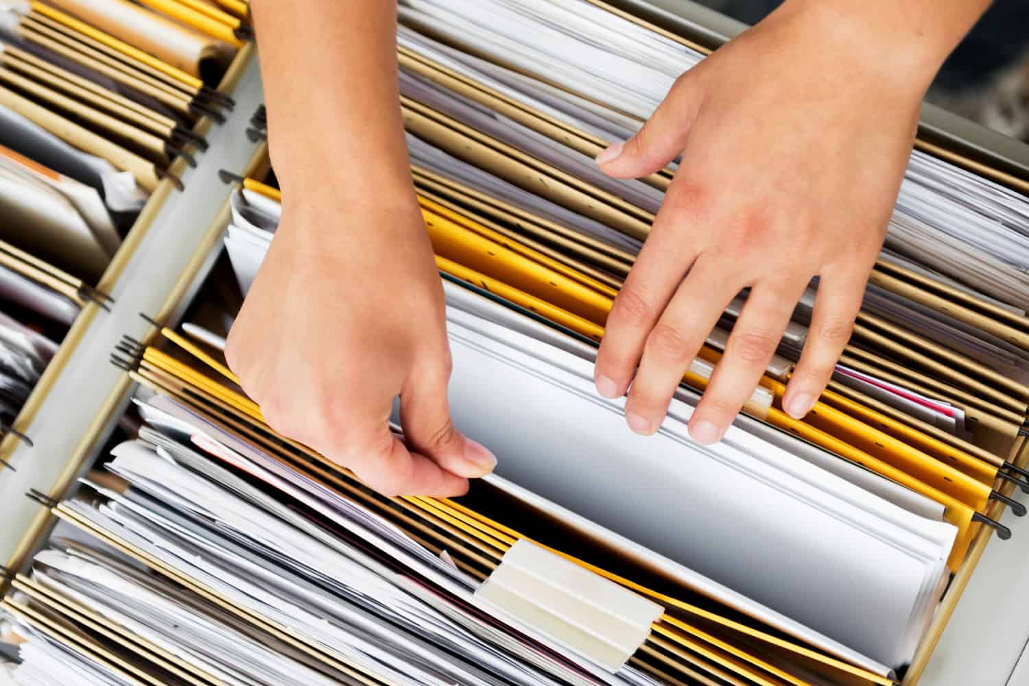 Close-up of hands searching in a file cabinet