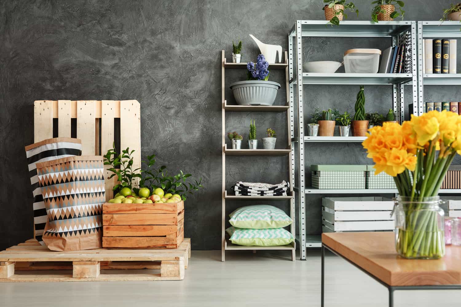 Grey and white room with plants on metal shelves and wooden pallets
