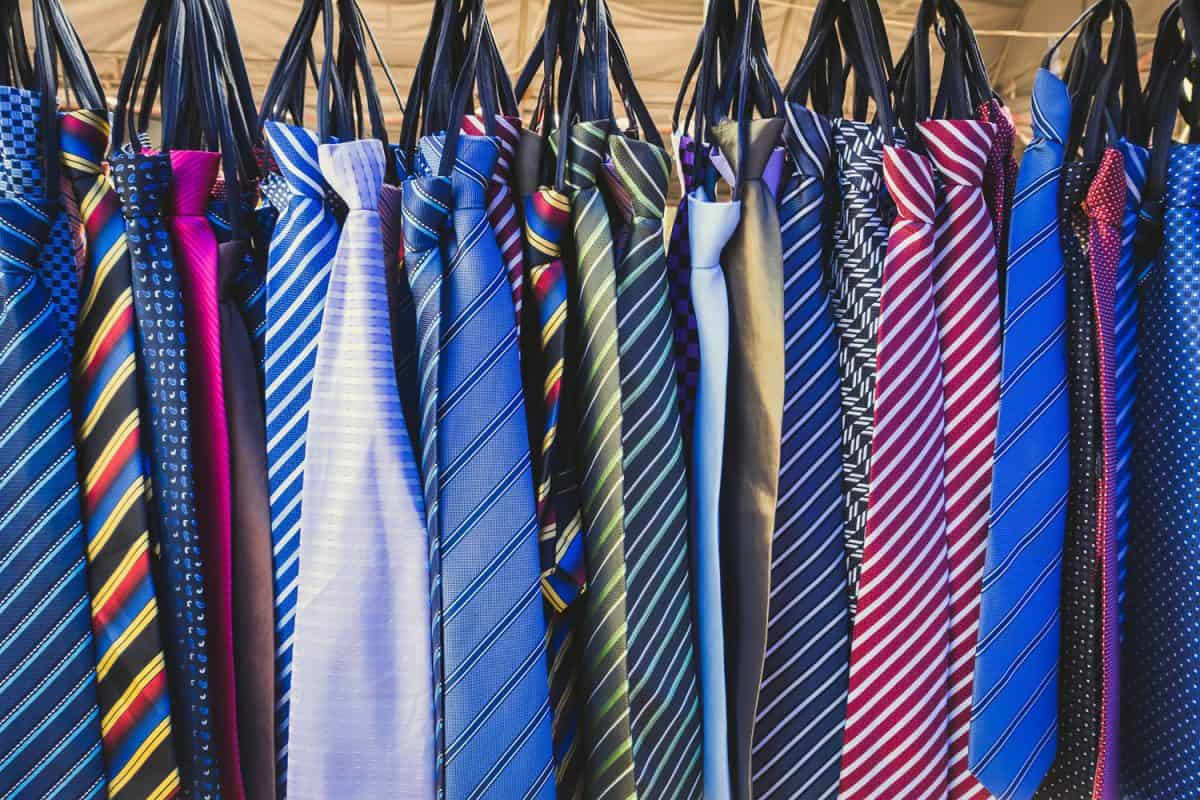 Large selection of colorful neckties hanging in the sale on the street market. Many various pattern colorful neckties hanging on clothes rack.