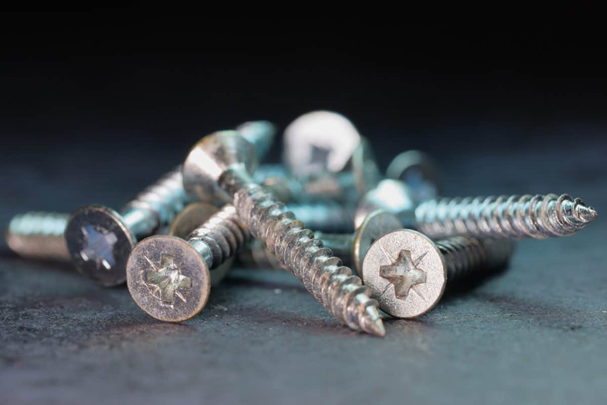 Macro photo of Screws in a pile - selective focus, shallow depth of field, dark background with cool blue light

