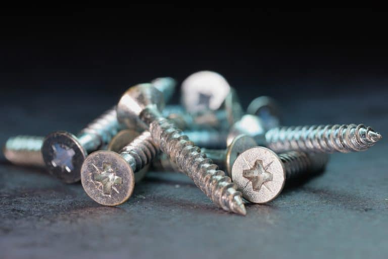 Macro photo of Screws in a pile - selective focus, shallow depth of field, dark background with cool blue light - What Screws To Use For Shelf Brackets