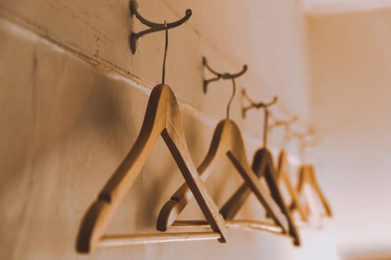 Row of empty wooden coat hangers on the wall in the dressing room, Are Cedar Clothes Hangers Worth It? [Pros & Cons Of Storing Clothes On Cedar]