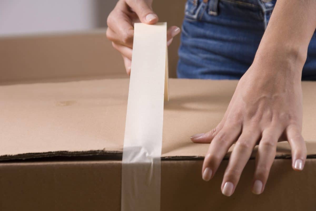 Woman sealing cardboard box with packing tape
