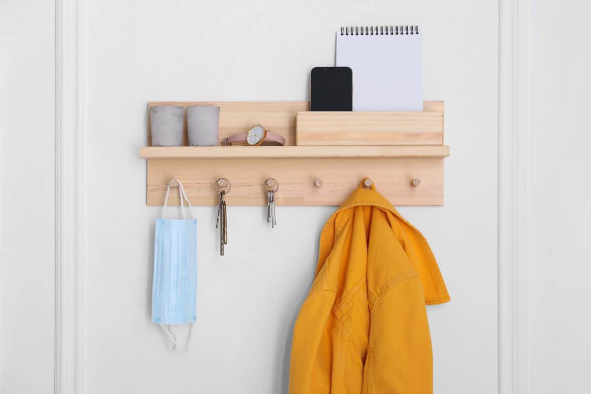 Wooden hanger for keys with different stuff on white wall
